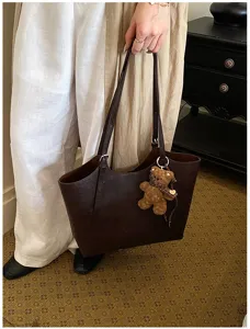 Détail élégant d'un sac cabas en cuir marron avec un joli pendentif ours pour femmes