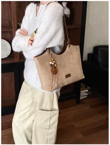 Gedetailleerd overzicht van stijlvolle retro suède tote tas met houten kralen hanger.
