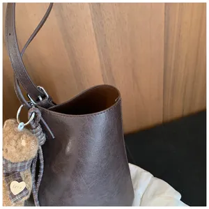 Sac seau en cuir marron vue détaillée avec bandoulière réglable et porte-clés ours.