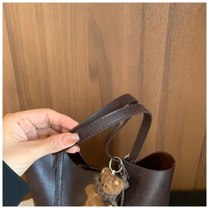 Gros plan sur la poignée du sac fourre-tout en cuir marron et son adorable pendentif.