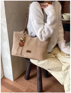 Gedetailleerd overzicht van de retro bruine suède tote tas met franje en schouderband.