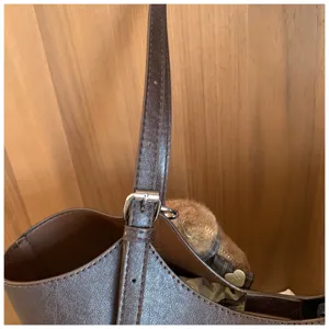 Detail de la sangle de sac a main en cuir PU marron avec boucle metallique et couture.
