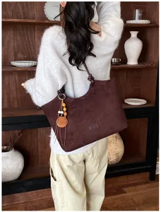 Gedetailleerd overzicht van retro donkerbruine suède schoudertas met houten kralenhanger decor.