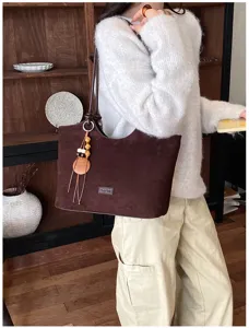 Gedetailleerd overzicht van een bruine suède tote bag met een houten kraal hanger.