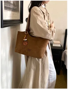 Gedetailleerd shot van een bruine vintage suède shopper met houten bedel voor dames.