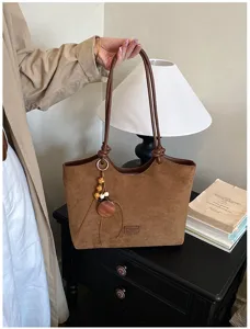 Detail van bruine retro suède shopper tas met fijne schouderbandjes en houten hanger.