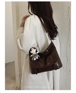 Chic patent leather messenger bag for women, retro shoulder bag with cute doll pendant charm.