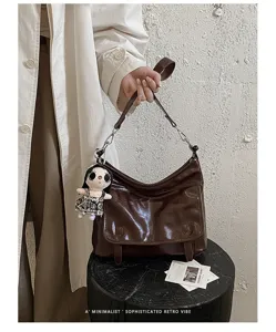 Chic retro patent leather shoulder bag for women, trendy messenger crossbody bag with doll charm.
