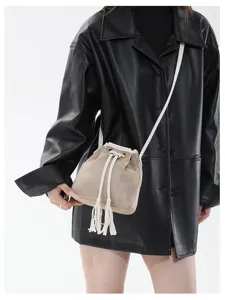 Retro frosted suede bucket bag detail shot showcasing delicate tassel and drawstring design.