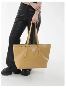 Detailaufnahme der gelben Ledertasche mit auffälligen Ösendetails und Doppelgriffen.