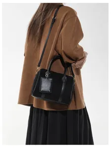 Schicke schwarze Boston Schultertasche in matter Optik mit Henkeln und Anhänger.