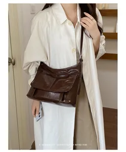 Detailed view of brown patent leather shoulder messenger bag, vintage style daily wear scene.