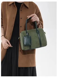 Detailaufnahme der dunkelgrünen Wildleder-Boston-Handtasche mit Vintage-Textur und Henkeln.