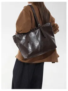 Braune glänzende Damentragetasche, große Schulter-Achseltasche mit metallischen Ösendetails.