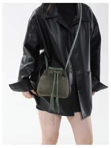 Green suede bucket bag detail shot showing drawstring tassels and metal ring accents.