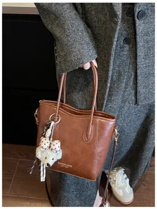 Borsa shopper in pelle marrone vista dettagliata con ciondolo cane, accessorio chic.