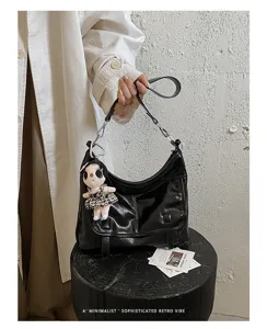 Detail view of black retro shoulder bag with plush doll charm and chic strap design.