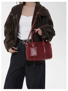 Detailansicht der roten Wildleder Boston Schultertasche mit weicher Textur und Vintage Beschlägen.