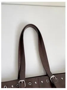 Nahaufnahme einer dunkelbraunen Ledertasche mit Metallchnallen und silberner Hardware.