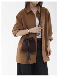 Detailed view of a retro brown suede bucket bag with chic tassel drawstrings and shoulder strap.