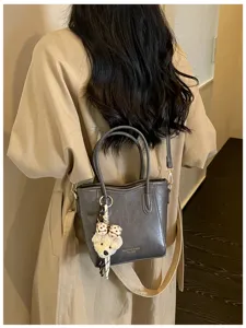 Elegante borsa a secchiello grigia da donna con manici e simpatico portachiavi orsetto quotidiano.