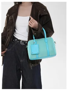 Detailaufnahme der stilvollen türkisen Wildleder Boston Handtasche mit Griffen und Anhänger.