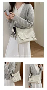 Chic retro messenger bag detail with leather, chain strap and doll pendant for style.