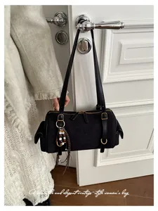Nahaufnahme Detail der schwarzen Wildleder Vintage Boston Schultertasche an der weissen Tür.