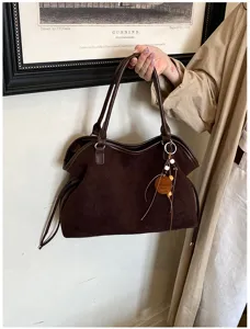 Detail view of dark brown retro suede tote bag with wooden charm and shoulder straps.