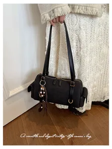 Detailansicht der schwarzen Wildleder Boston Handtasche mit Metallbeschlägen und Anhängern.
