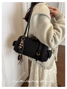 Nahaufnahme der schwarzen Wildleder Boston Schultertasche mit raffiniertem Perlenanhänger.