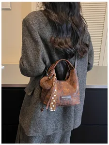 Detailansicht einer retro Leo-Muster Handtasche mit flauschigem Bommel und Pünktchen Schleife.