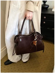 Brown suede tote bag detail featuring soft texture, slouchy silhouette, and wooden bead pendant.