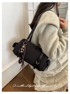 Schwarze Vintage Wildleder Boston Schultertasche Detail mit Quastenanhänger und großem Design.