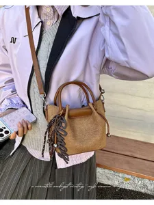 Detailed shot of trendy vintage brown bucket bag with handle, strap and chic charm.