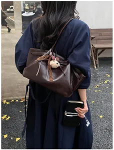 Detailed view of vintage brown soft leather tote bag with cute bear pendant and ribbon.