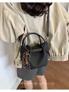 Stylish black bucket bag with top handle and crossbody strap, perfect for autumn casual wear.