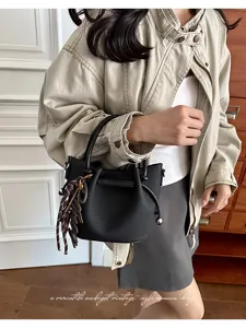 Black pleated bucket bag accessory detail view, stylish women's handbag with charms.