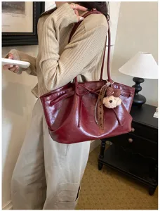 Burgundy leather tote bag with cute bear charm, vintage shoulder bag for women daily commute.