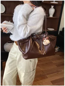 Detailed view of the retro brown tote shoulder bag with cute puppy pendant, daily commute style.