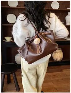 Vintage brown PU leather shoulder bag for women, large capacity daily commuter tote with cute charm.