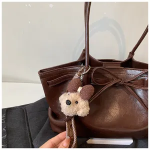 Simple retro large-capacity tote bag detail showing cute bear pendant and leather texture.