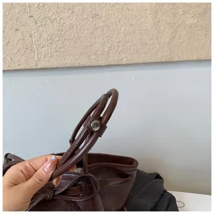 Brown PU leather tote bag handle detail closeup featuring polished metal snap closure