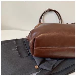 Close-up detail of vintage brown faux leather tote bag showing fine texture details.
