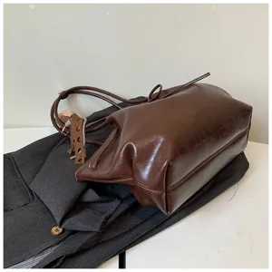 Detail view of the minimalist brown leather tote bag showcasing texture and strap design.
