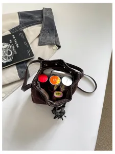 Stylish retro suede bucket bag for women with fringe drawstring and versatile shoulder strap.