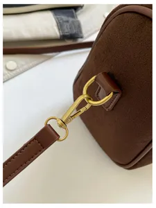 Nahaufnahme der braunen Wildleder Boston Tasche Metallbeschläge und Riemendetail.