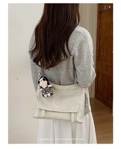 Detailed view of the stylish retro messenger bag with chic doll pendant and strap.