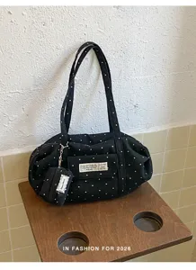 Detail view of black canvas tote bag featuring cute white polka dots and stitched label.