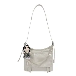 Chic light gray PU leather messenger bag for women with trendy doll pendant and crossbody strap.